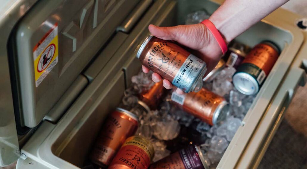 canned cocktails in a cooler with ice at a tailgate party